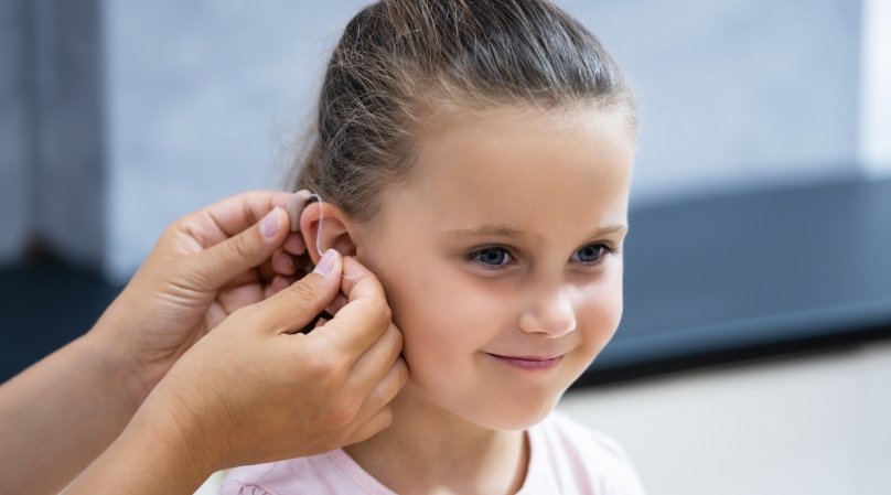 Bambina felice con apparecchio acustico